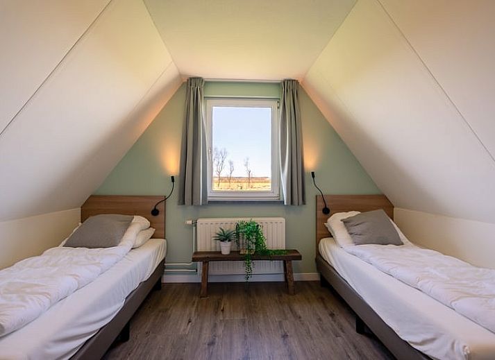 Gemuetliches Wohnzimmer im Ferienhaus in De Waal, Texel mit bequemem Ecksofa und Blick auf die gruene Umgebung.