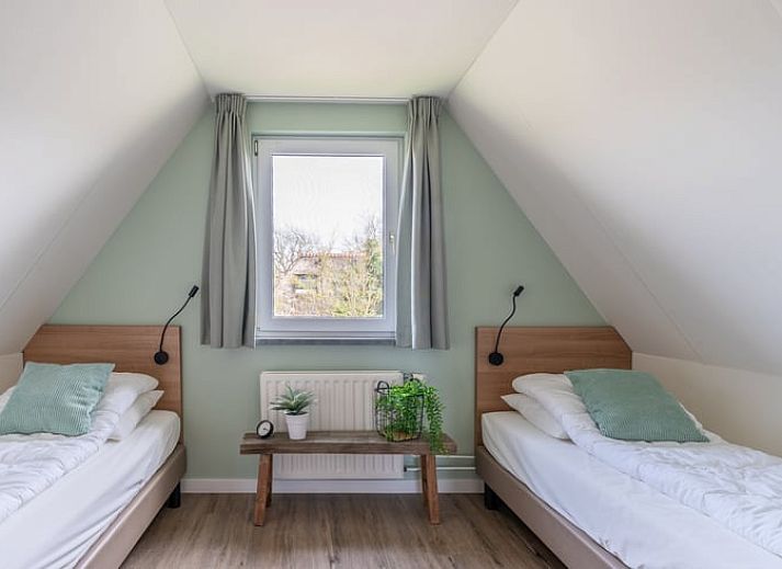 Gemuetliches Wohnzimmer im Ferienhaus in De Waal, Texel mit bequemem Ecksofa und Blick auf die gruene Umgebung.