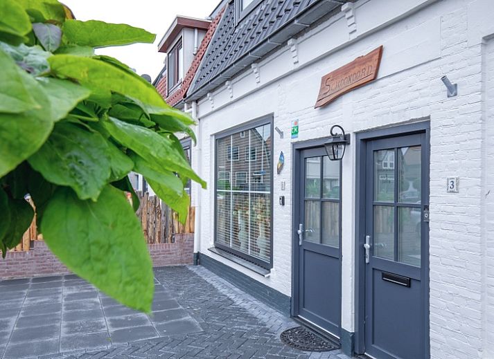 Vorderansicht des Ferienhauses Schoonoord in Den Burg, Texel, mit gruenen Akzenten und einem einladenden Eingang.