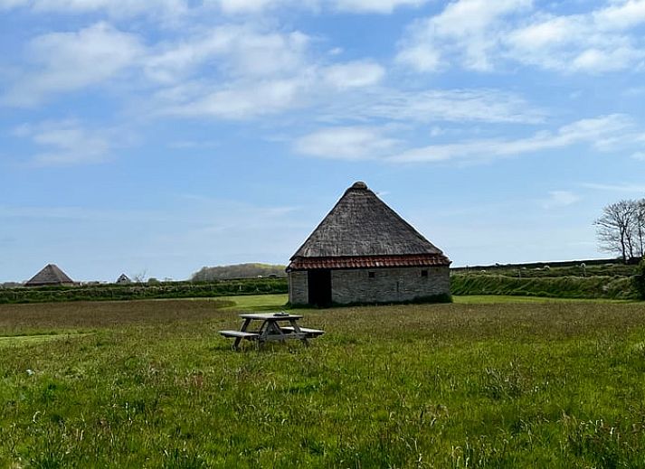 Ferienhaus in Den Burg auf Texel, in malerischer Umgebung mit weiten Feldern und charakteristischem Reetdach.