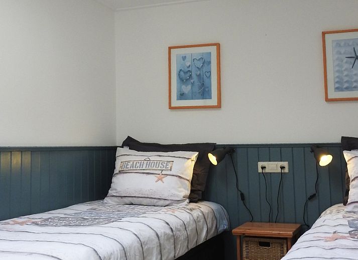 Gezellige woonkamer in familie Smit bungalow Den Burg Texel met comfortabele bank en decoratieve kunst.