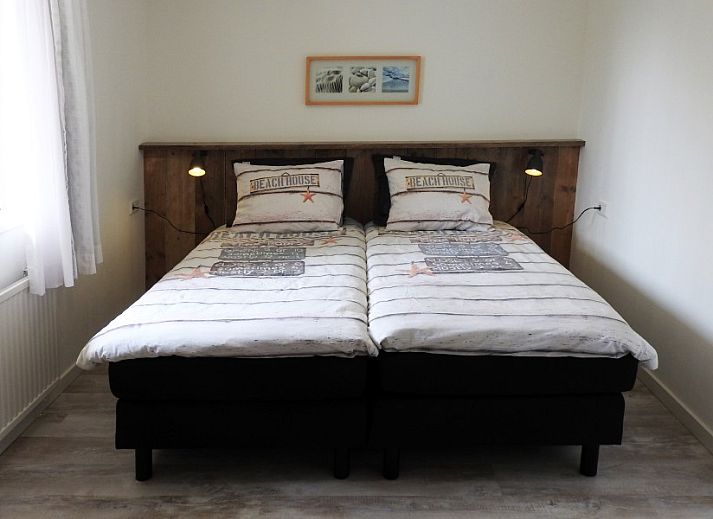 Gezellige woonkamer in familie Smit bungalow Den Burg Texel met comfortabele bank en decoratieve kunst.