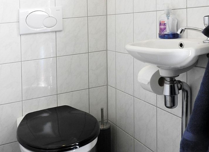 Gezellige woonkamer in familie Smit bungalow Den Burg Texel met comfortabele bank en decoratieve kunst.