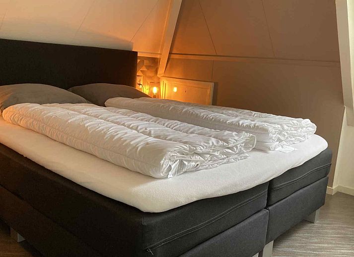 Schlafzimmer im Ferienhaus NH197 Texel mit bequemem Bett und Holztisch