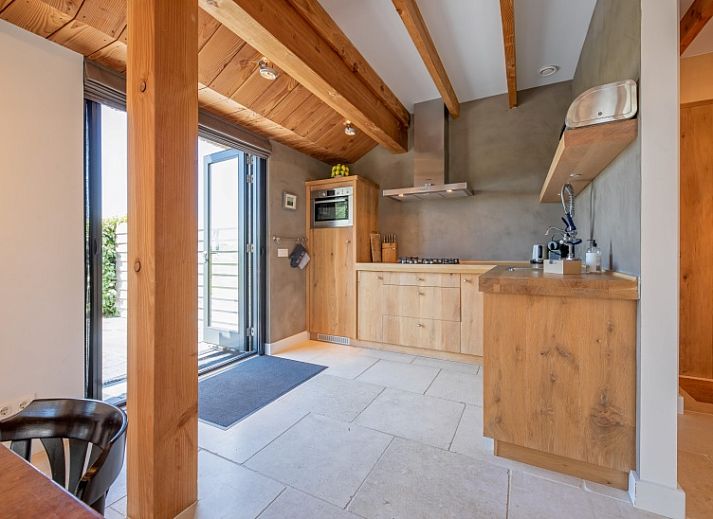 Cozy dining room in Buitenplaats vacation home Den Burg Texel with wooden table and open staircase.