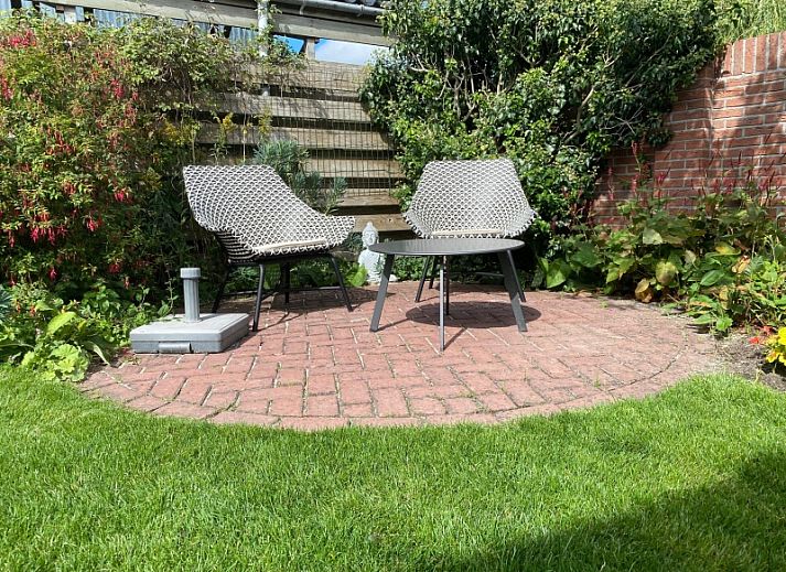 Stadhuisje Texel in Den Burg, charmant vakantiehuis met groene gevel en bloemenrijke omgeving op de Waddeneilanden.