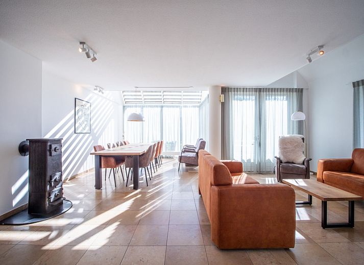 Korenmolen-Ferienhaus in Den Burg, Texel, umgeben von einem gruenen Garten und blauem Himmel.