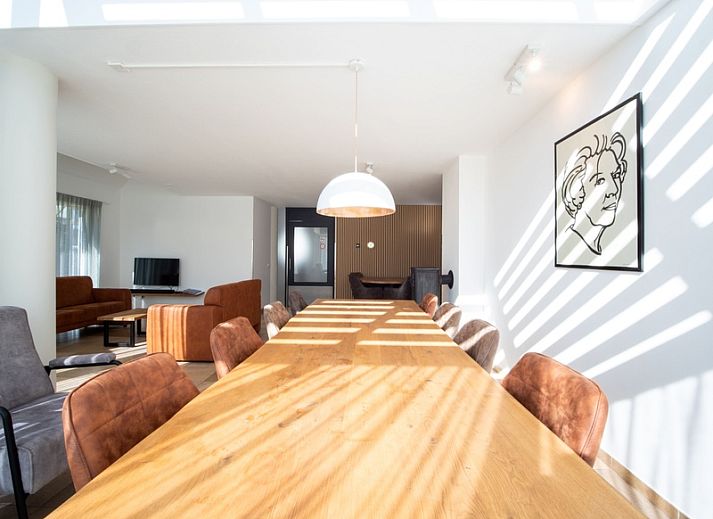 Korenmolen-Ferienhaus in Den Burg, Texel, umgeben von einem gruenen Garten und blauem Himmel.