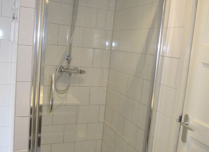 Sonnige Terrasse an De Molen, Ferienhaus in Den Burg, Texel mit Gartenmoebeln und bluehenden Pflanzen.