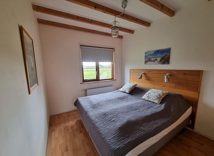 Seitenansicht des Ferienhauses Duinzicht in Den Burg Texel mit roten Dachziegeln und Rasen.