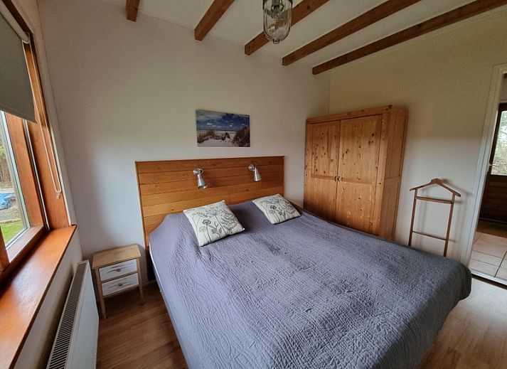 Seitenansicht des Ferienhauses Duinzicht in Den Burg Texel mit roten Dachziegeln und Rasen.