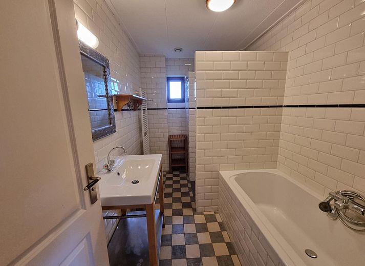 Seitenansicht des Ferienhauses Duinzicht in Den Burg Texel mit roten Dachziegeln und Rasen.