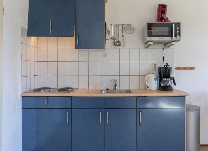 Gemuetliches Wohnzimmer des Ferienhauses Onderhuus in Den Hoorn Texel mit rotem Sofa.