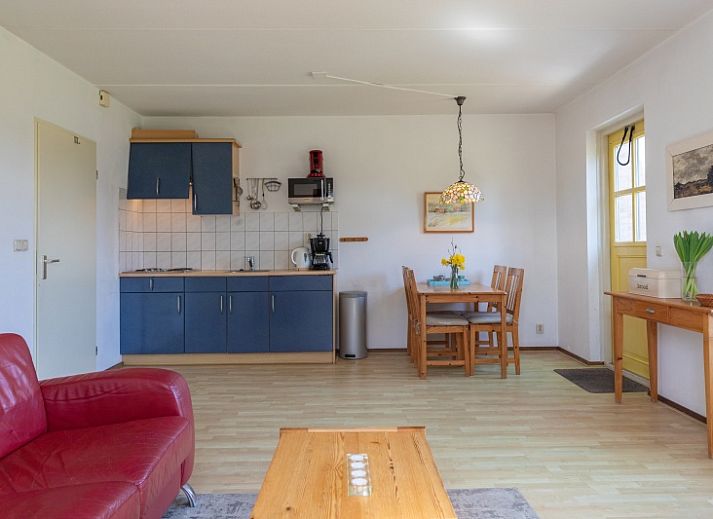 Gemuetliches Wohnzimmer des Ferienhauses Onderhuus in Den Hoorn Texel mit rotem Sofa.