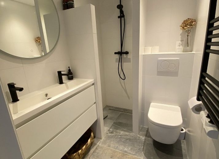 Aussenbereich des Doppelstudios 1 in Den Hoorn, Texel, mit einer sonnigen Terrasse und einem bunten Garten.