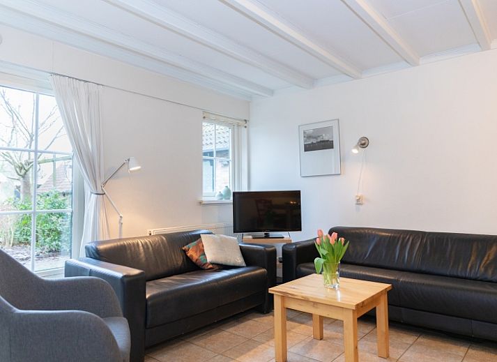 Charmantes Ferienhaus Schaapskooi in Den Hoorn, Texel, mit gruener Fassade und umliegender Natur.