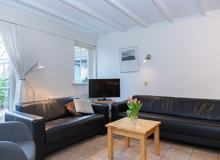 Charmantes Ferienhaus Schaapskooi in Den Hoorn, Texel, mit gruener Fassade und umliegender Natur.