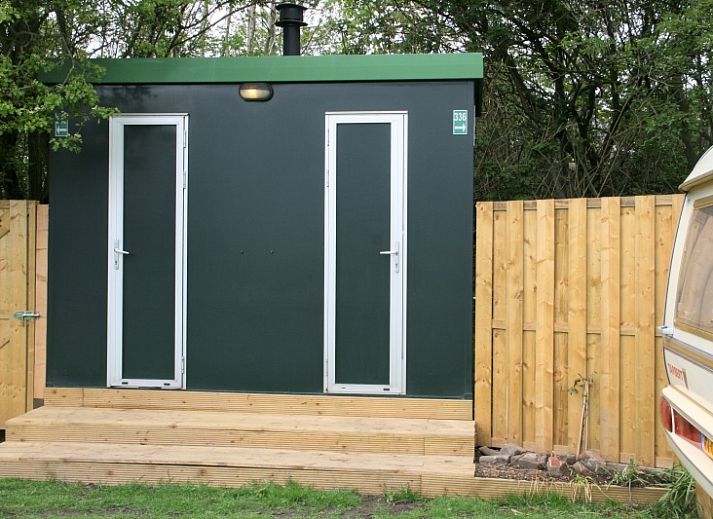 Essecke im Caravan Rust & Ruimte, Den Hoorn, Texel, mit Holztisch und Korbstuehlen fuer eine gemuetliche Atmosphaere.