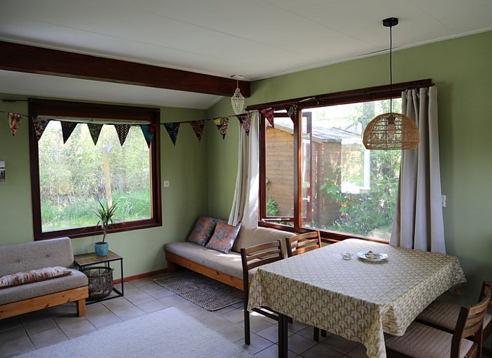 Ferienhaus Vogelsand in Den Hoorn Texel mit gruener Umgebung und Holzfassade.