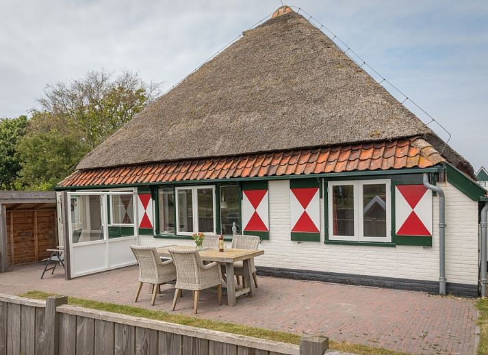 Buitenzicht van Appartement Heem, een charmante vakantiewoning in Den Hoorn, Texel, met traditioneel rieten dak en gezellige veranda.