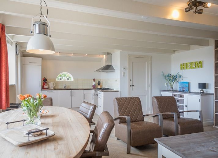 Buitenzicht van Appartement Heem, een charmante vakantiewoning in Den Hoorn, Texel, met traditioneel rieten dak en gezellige veranda.
