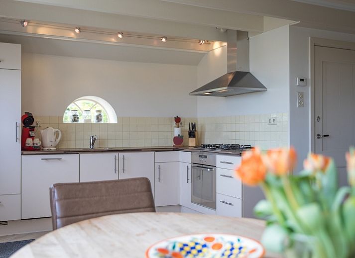 Buitenzicht van Appartement Heem, een charmante vakantiewoning in Den Hoorn, Texel, met traditioneel rieten dak en gezellige veranda.