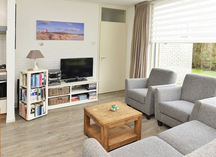 Side view of Bungalowpark De Noordel - De Polderdijkjes in Oosterend, Texel. Vacation home with green hedges and access path.