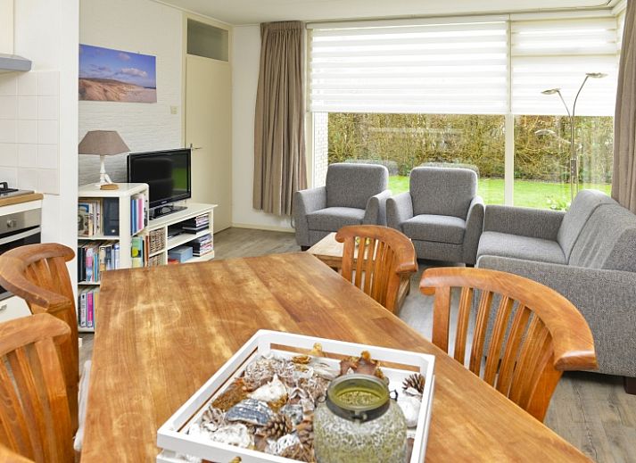 Side view of Bungalowpark De Noordel - De Polderdijkjes in Oosterend, Texel. Vacation home with green hedges and access path.