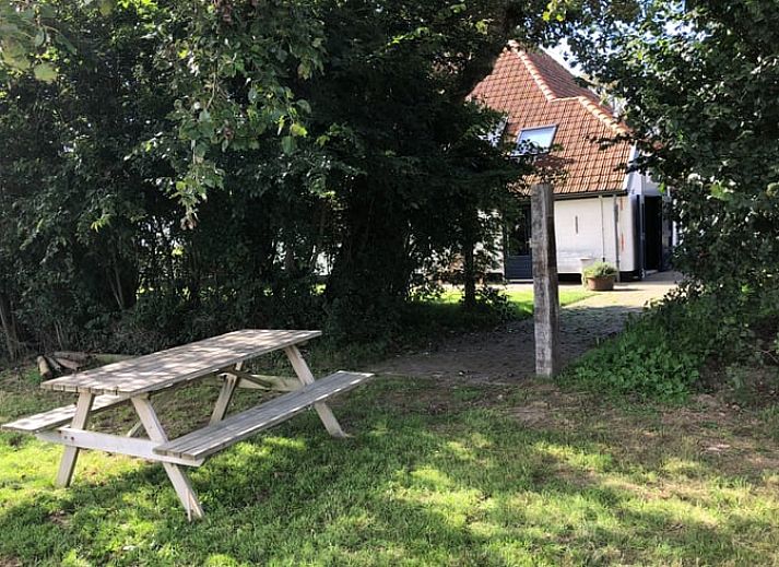 Seitenansicht des Ferienhauses in Oosterend, Texel mit gemuetlicher Sitzecke im Freien.
