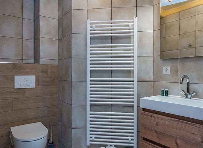 Terrasse des Ferienhauses in Oosterend, Texel, Ferienhaus mit Tisch im Freien, umgeben von Gruen auf den Watteninseln.