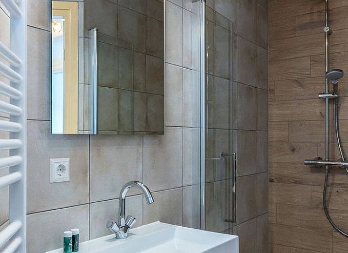 Terrasse des Ferienhauses in Oosterend, Texel, Ferienhaus mit Tisch im Freien, umgeben von Gruen auf den Watteninseln.