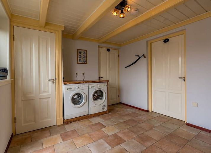 Terrasse des Ferienhauses in Oosterend, Texel, Ferienhaus mit Tisch im Freien, umgeben von Gruen auf den Watteninseln.