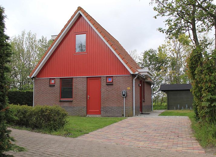 Typ II+ - Nr. 77 Goldfinch, Ferienhaus in Oosterend Texel mit roter Fassade und gruenem Garten.