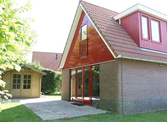 Typ II+ - Nr. 77 Goldfinch, Ferienhaus in Oosterend Texel mit roter Fassade und gruenem Garten.