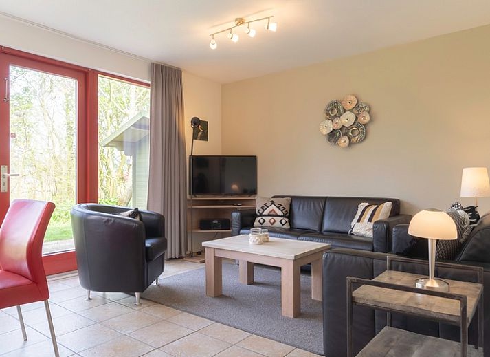 Typ II+ - Nr. 77 Goldfinch, Ferienhaus in Oosterend Texel mit roter Fassade und gruenem Garten.