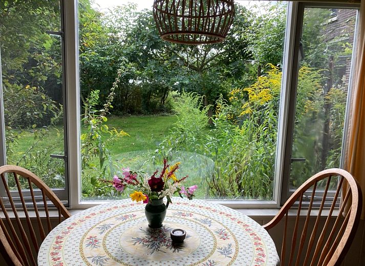 Ferienhaus De Bemes in Oosterend Texel mit gruener Fassade und blumenreichem Garten.
