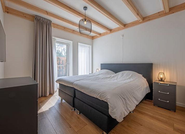 Gemuetliches Wohnzimmer im Cottage in Oudeschild, Texel, mit Holzbalken und komfortablen Moebeln.