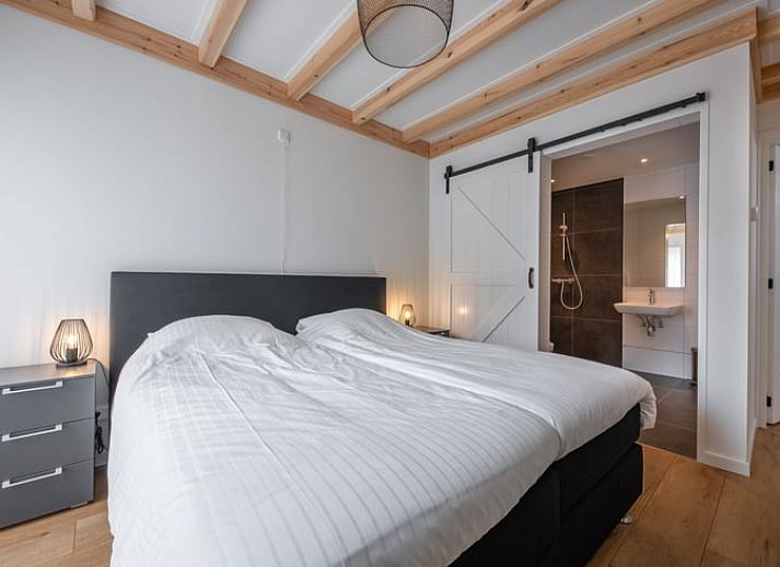 Gemuetliches Wohnzimmer im Cottage in Oudeschild, Texel, mit Holzbalken und komfortablen Moebeln.