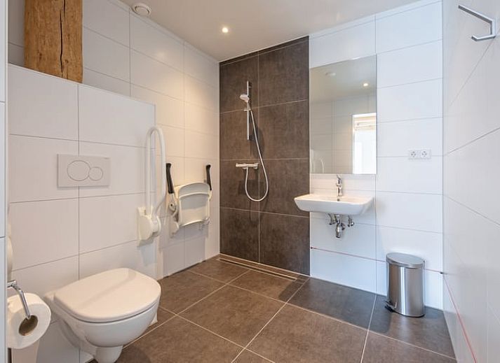 Gemuetliches Wohnzimmer im Cottage in Oudeschild, Texel, mit Holzbalken und komfortablen Moebeln.