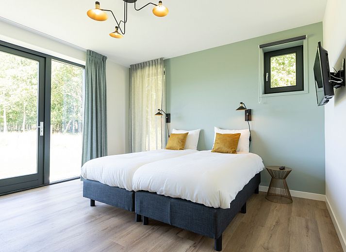 Spacious terrace of Holiday home 2 on Texel with parasol and wooden garden furniture.