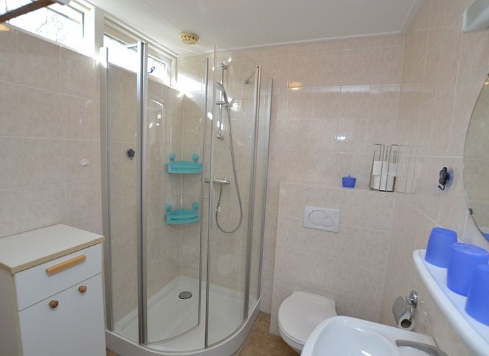 Gezellige woonkamer in Vakantiehuis de Parel 212, De Dennen, Texel met uitzicht op groene omgeving.