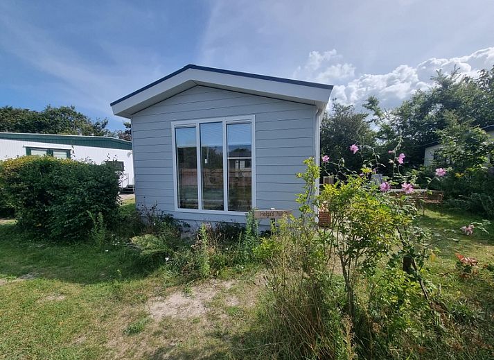 Ferienpark de Bremakker - Bosveld 135, Ferienhaus in De Dennen, Texel, umgeben von gruener Natur und blauem Himmel.