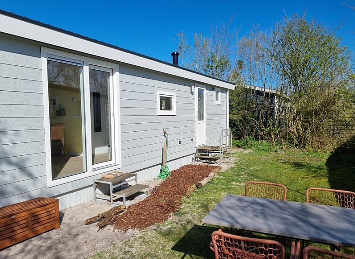 Ferienpark de Bremakker - Bosveld 135, Ferienhaus in De Dennen, Texel, umgeben von gruener Natur und blauem Himmel.
