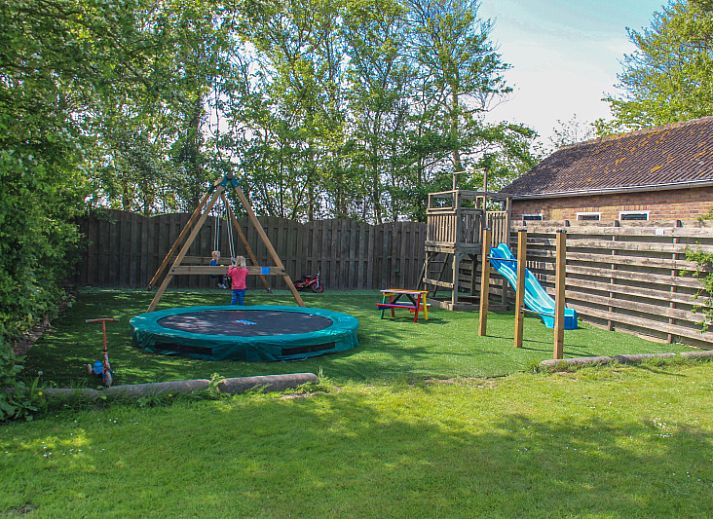 Stijlvolle eetruimte in Vakantiehuis Duif, De Dennen, Texel met uitzicht op de groene tuin van de Waddeneilanden.