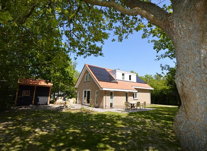 Ferienhaus De Nagtegaal 23 in De Dennen, Texel, umgeben von Natur mit einer sonnigen Terrasse.