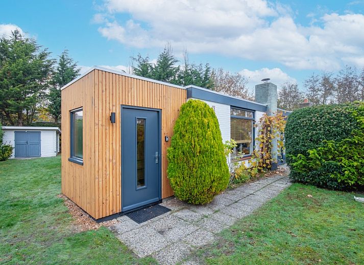 Bungalowpark 't Luwe Land - 7B - De Wijnhof, Ferienhaus in De Dennen, Texel, mit gruenem Garten und blauem Himmel.