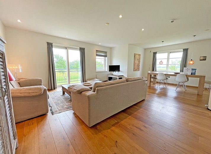 Gezellige woonkamer van Appartement Bos en Duin 40 in De Dennen, Texel met comfortabele banken en uitzicht op de natuur.