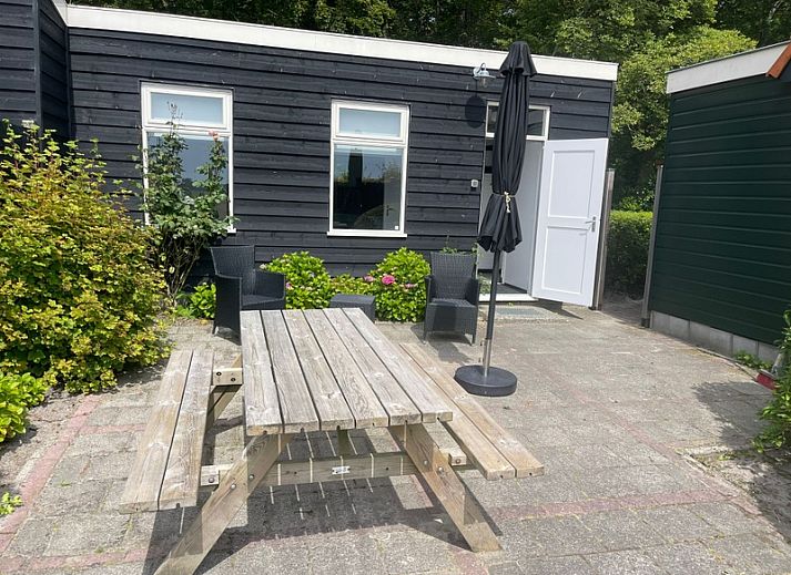 Exterior of vacation home Wollewei in De Dennen, Texel, surrounded by green nature.