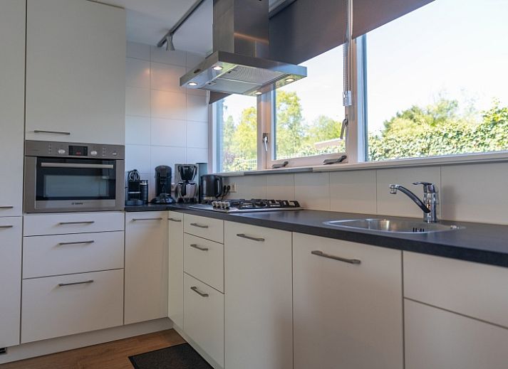 The vacation home at Bungalowpark De Parel - WELMOED on Texel has an inviting terrace and green lawns.