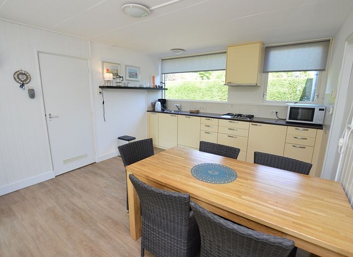 Gemuetliches Wohnzimmer des Ferienhauses de Parel 282, De Dennen, Texel, mit Blick auf den gruenen Garten.